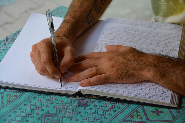 person writing on a physical April 2026 wall calendar next to a laptop showing a digital calendar